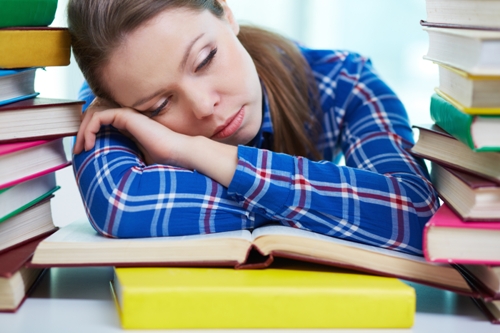 Træt elev sover over lærebøger