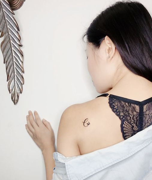 Aranyos C betűs tetoválás a hátán