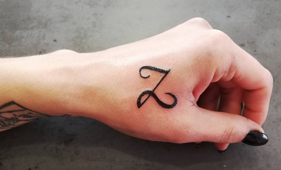 Aranyos Z betűs tetoválás a hüvelykujj közelében