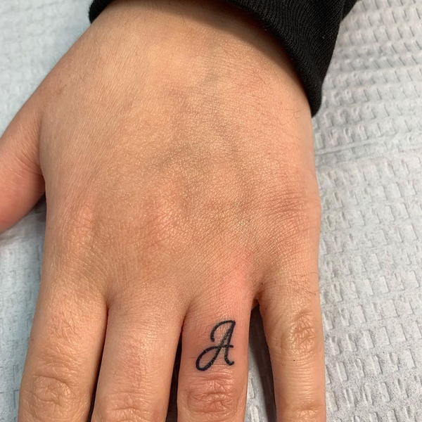 Et brev tatovering på ringfingeren