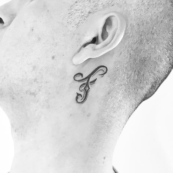 Stilfuld F Letter -tatovering nær øret