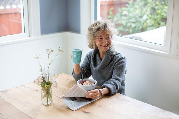 Laihtuminen ikäinen nainen yksin aamiaisella juo pienen osan teetä sanomalehden lukemisesta