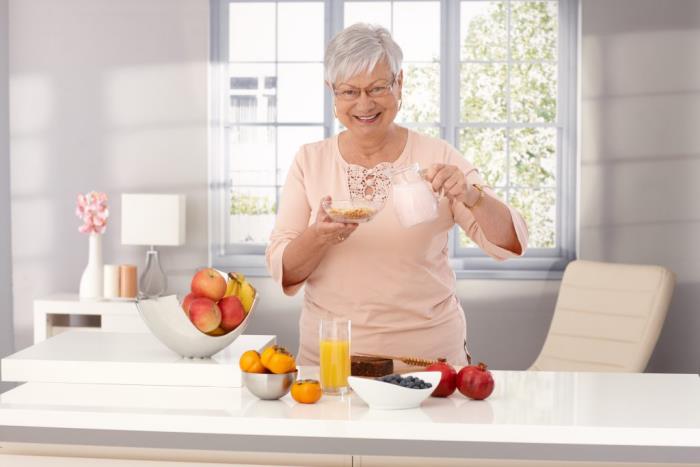 Laihtua ikäinen nainen keittiössä aloittaa päivän kevyellä aamiaismehulla ja paljon hedelmiä