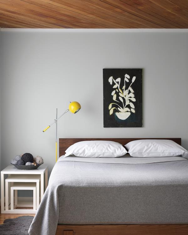 Nykyiset seinän värit harmaa makuuhuone vaaleanharmaa seinällä päiväpeite valkoiset tyynyt pieni kohokohta keltaisessa lampussa
