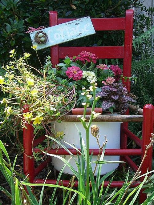 Vanhat tuolit puutarhassa uuden toiminnon punaisilla houkuttelevilla istutuskoneilla