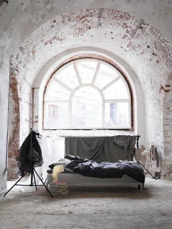 Tiiliseinä makuuhuoneessa maalaismaisella kosketuksella ainutlaatuinen kaari -ikkuna paljastettu tiiliseinä