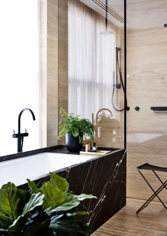 Kylpyhuoneen trendit 2021 kylpyammeen ulkopinta musta marmori-ikkuna eksoottinen vihreä kasvi katseenvangitsija