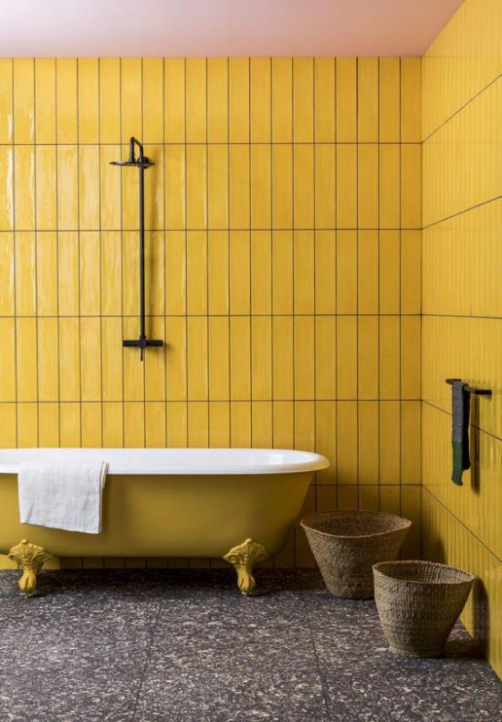 Kylpyhuoneen trendit 2021 retro design keltaiset seinäpaneelit keltainen kynsi jalka kylpyamme tumma terrazzo lattia