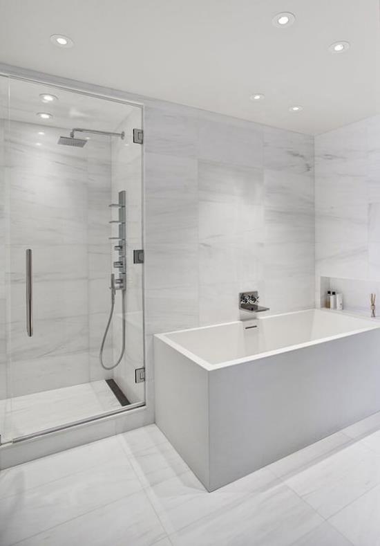 Kylpyhuone kokonaan valkoisessa kylpyammeessa suihku kulma lasiseinä katto kohdevalot keinovalo
