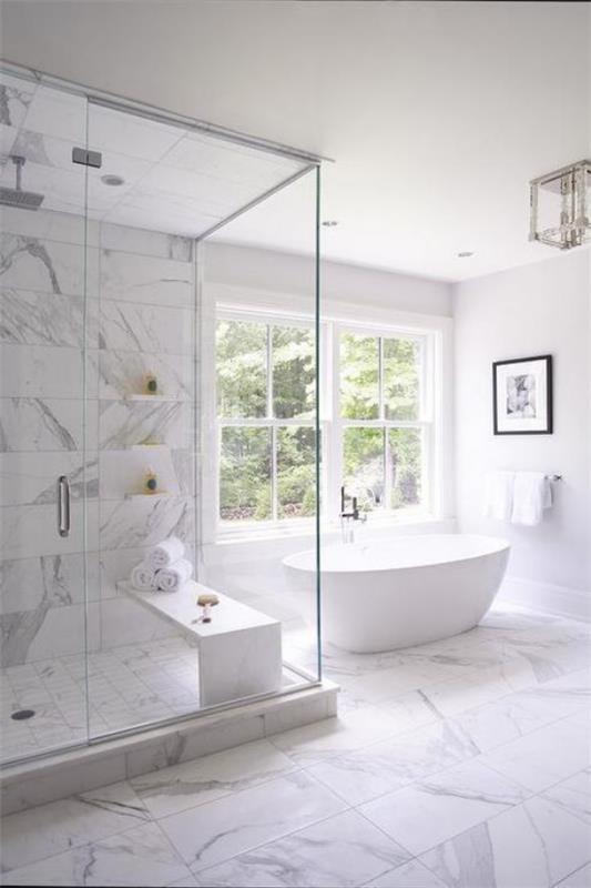 Kylpyhuone kaikki valkoiset marmorilaatat paljon luonnonvaloa vapaasti seisova kylpyamme suihku lasiseinät