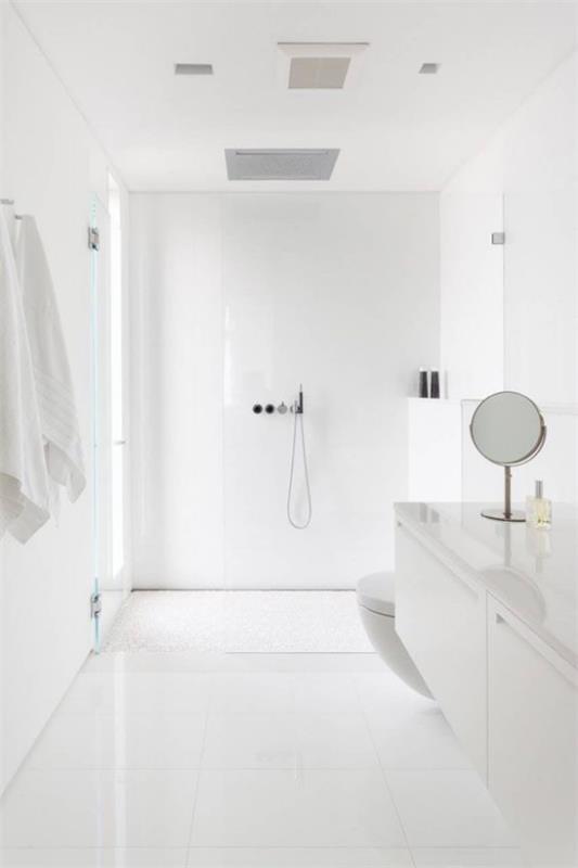 Kylpyhuone kokonaan valkoinen, puhdasta minimalismia, valkoiset pyyhkeet, pienet pyöreät peilit