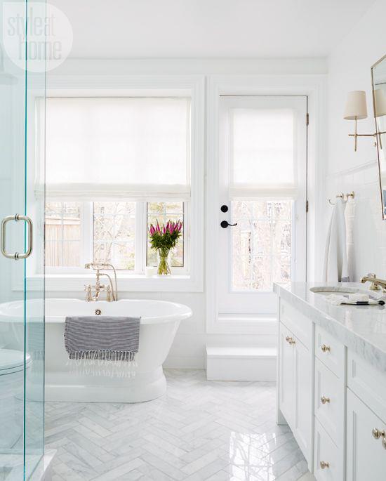 Kylpyhuone kokonaan valkoisessa tyylikkäässä kylpyhuoneessa muotoilee tyylikäs maljakko värikkäistä kukista ikkunan vieressä
