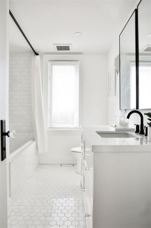 Kylpyhuone kaikki valkoiset valkoiset metrolaatat seinälle eri muotoiset lattialla mustat varusteet ikkunat paljon luonnonvaloa