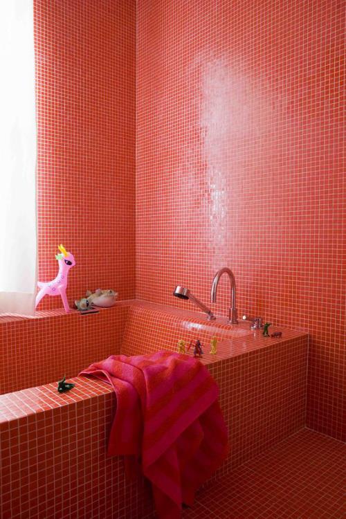 Kylpyhuone punaisissa kylpyammeen seinissä lattia peitetty pienillä punaisilla laattoilla valkoinen laasti punainen pyyhe
