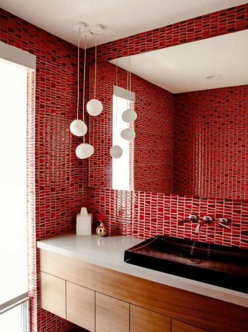 Kylpyhuone punaisella, punaiset laatat seinillä, suuret seinäpeilit, valkoiset riippuvalot, valkoinen turhamaisuus, pienet kylpyhuonetarvikkeet