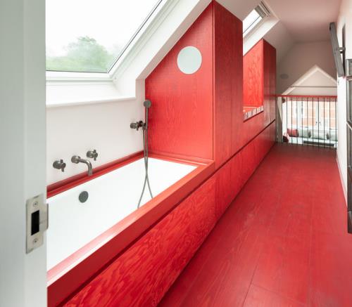 Kylpyhuone punaisella rinteessä alla paljon päivänvaloa punaista paneeli -ammea kattoikkunan punaisten kaapien alla