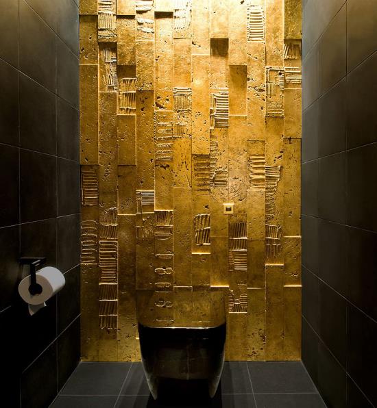 Kylpyhuone musta ja kultainen wc yksi seinä kultaa hohtaa mielenkiintoinen pinta muut kaksi seinää lattia ja wc -kulho musta