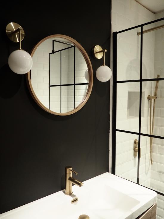 Musta ja kultainen kylpyhuone rikkoo värimaailman valkoisen peilin kultainen runko kaksi riippuvalaisimen hanaa kultaa