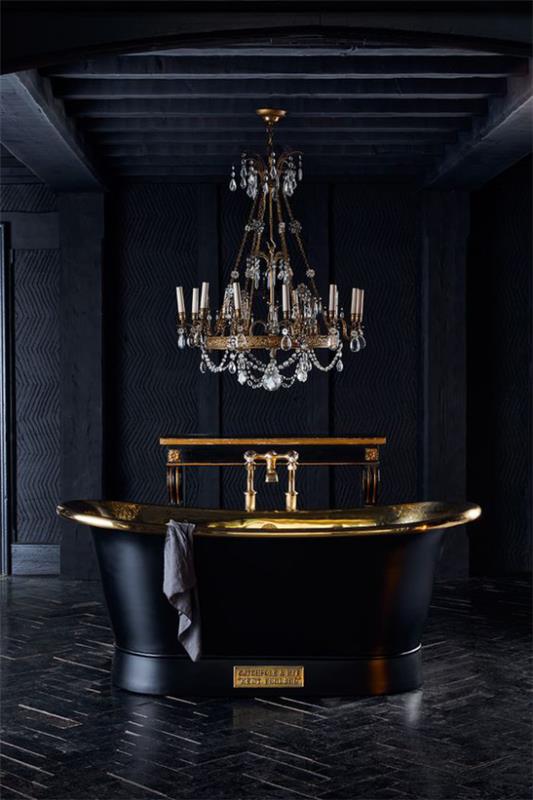 Musta ja kultainen kylpyhuone, tumma tunnelma, vapaasti seisova kylpyamme, kiiltävät kultaelementit ja ylelliset kattokruunut