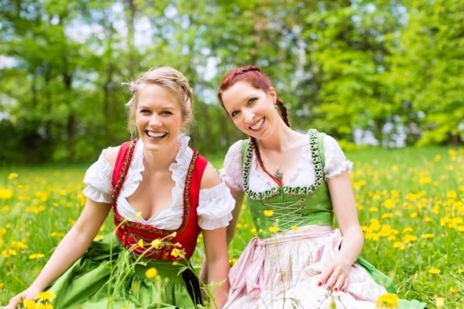 Nuoret naiset perinteisissä baijerilaisissa vaatteissa - dirndl tai tracht - niityllä keväällä