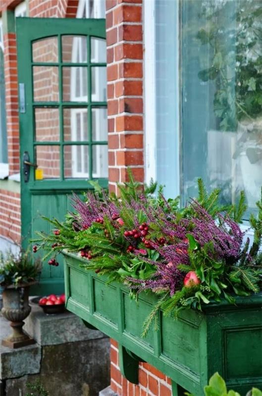 Kukkalaatikko ikkunalaudalla vihreässä maalaistalossa rehevissä kasveissa värikkäitä kukkia