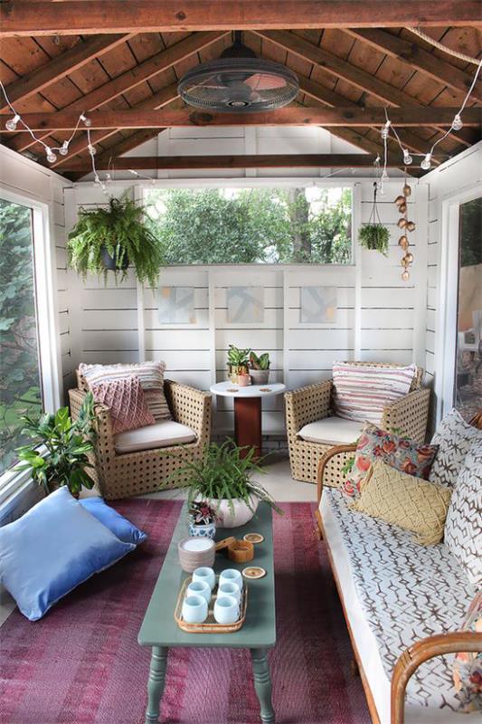 Boho -tyylinen veranta -nojatuoli, joka on valmistettu rottinkisohvalta, rehevän vihreiden kasvien koristetyynyt