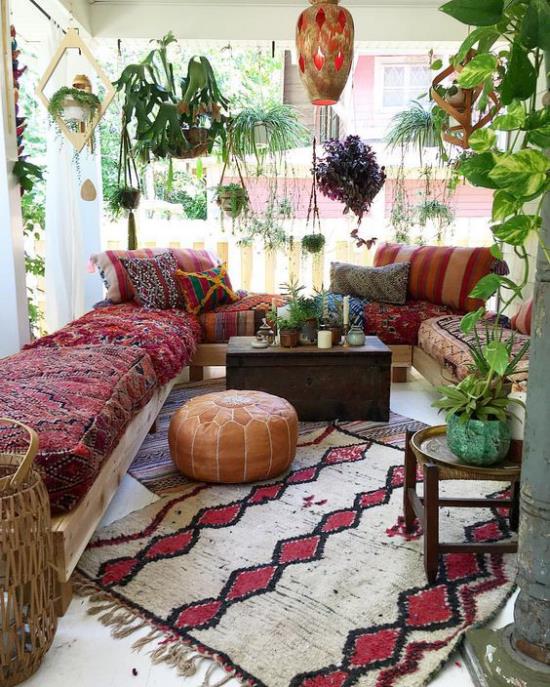 Boho-tyylinen kuistimatto luonnonvalkoisessa ja viininpunaisessa sohvassa värikäs huopa, jossa on paljon vihreitä kasveja