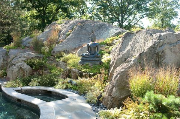 Buddha -hahmot puutarhassa vihreät lehdet kivet kiviä