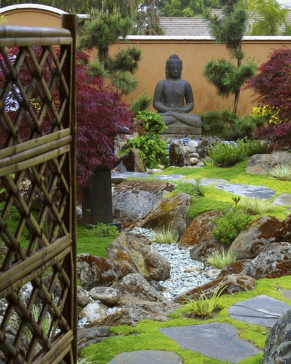 Buddha -hahmot rentoutuvat puutarhan vehreässä ympäristössä