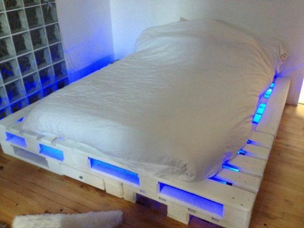 Puulavoista valmistetut vuoteet on valaistu sinisellä