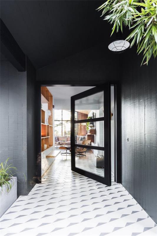 Kotiin pyörivät ovet, jotka on valmistettu metallista mustista ovikehyksistä, antavat kolmen suuren lasiruudun tulvata paljon valoa
