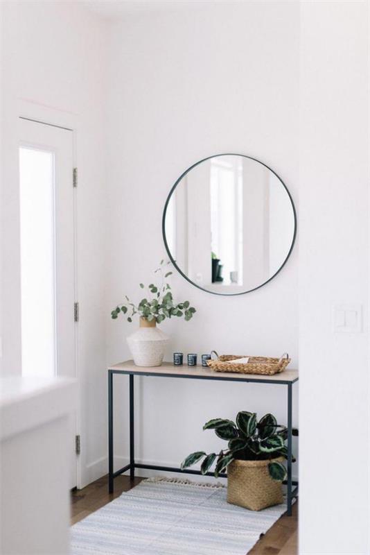 Sisäänkäynti moderni muotoilu yksinkertainen eteinen huonekalut pöytä vihreä kasvi valkoinen maljakko vihreillä oksilla kevyt matto pyöreä peili