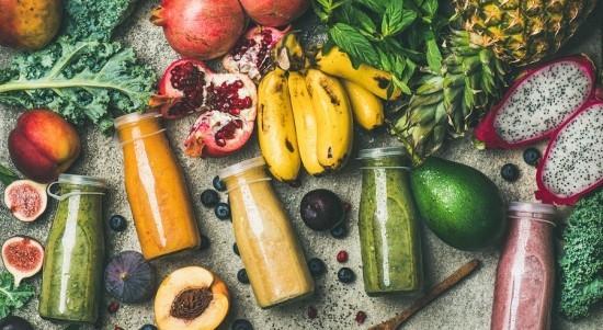 Värikkäitä fitness -smoothieja pienissä pulloissa tuoreita hedelmiä vihanneksia