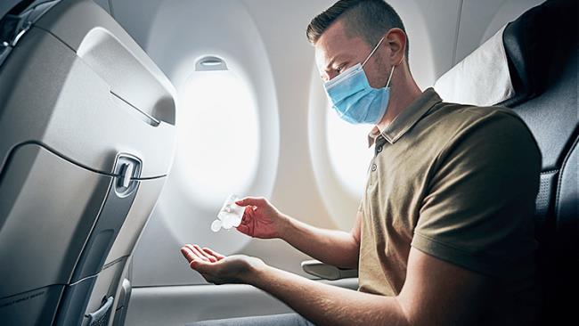 Lentot korona -aikana Lentokoneessa matkustajat käyttävät desinfiointiainetta desinfioimaan käsiään