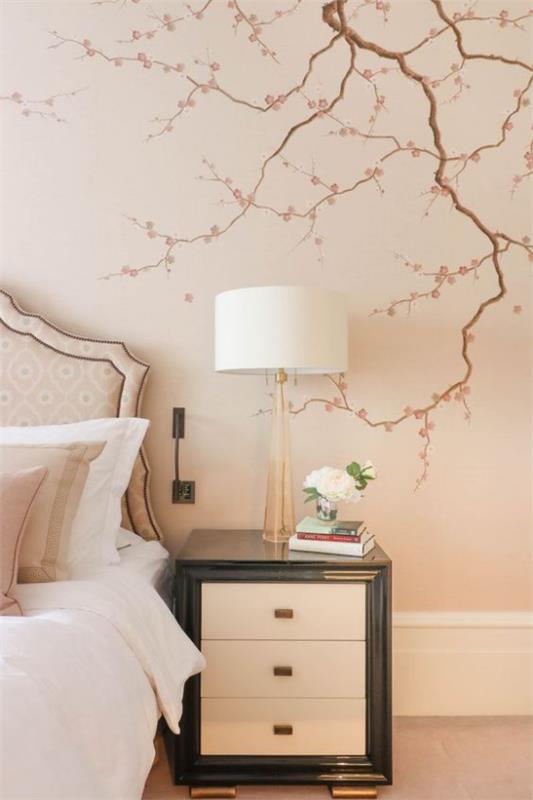 Kevään koristelu kirsikankukkien seinätarralla makuuhuoneessa vaaleanpunaisella taustalla