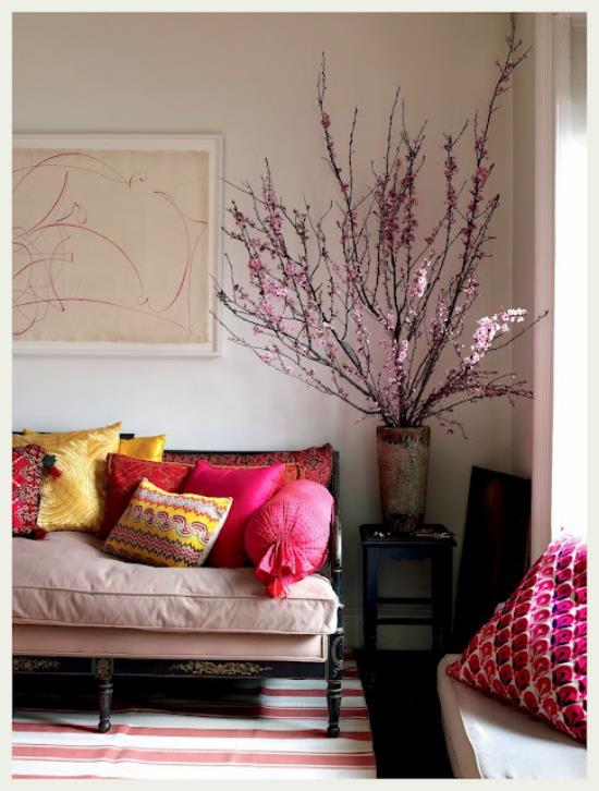 Kevään koristelu kirsikankukilla iso maljakko kauniisti järjestetyillä kirsikka oksilla olohuoneen kulmassa värikkäät heitotyynyt