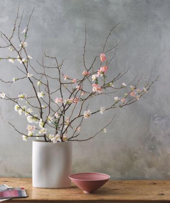 Kevään koristelu kirsikankukilla minimalistisella suunnittelulla valkoinen maljakko valkoinen ja vaaleanpunaiset kukat pieni vaaleanpunainen kulho sen vieressä