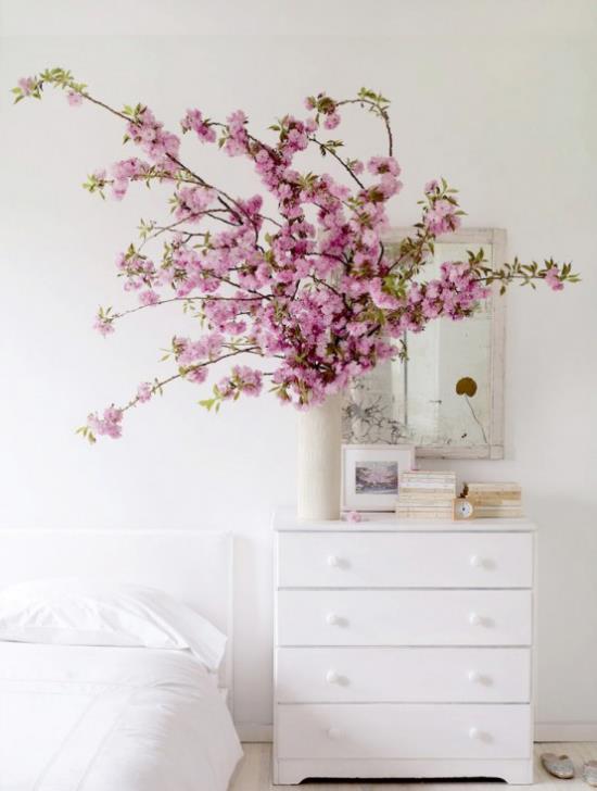 Kevään koristelu kirsikankukilla vaaleanpunaisilla kukilla maljakossa valkoinen lipasto -seinäpeili
