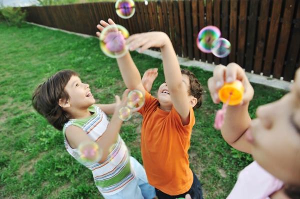 Puutarhapelit lapsille, jotka leikkivät ulkona jahtaavat saippuakuplia