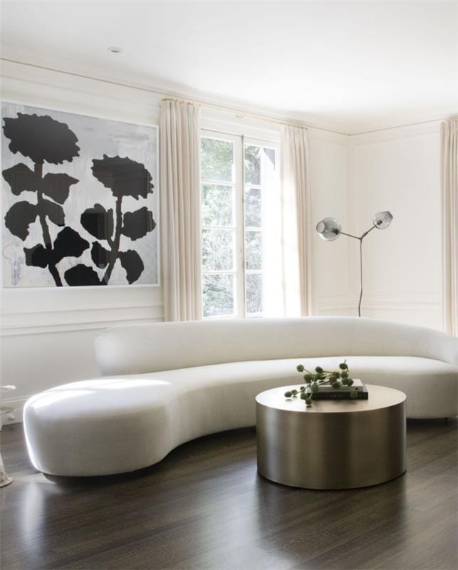Sisustussuunnittelun salaisuudet paljastuvat tyylikkäästi sisustetussa olohuoneessa, pyöreä valkoinen sohva, pyöreä sohvapöytä metallisella loistolla, tumma lattia kontrastina