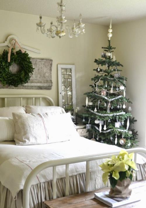 Viihtyisissä makuuhuoneissa on suuri sänky, valkoiset ja kermaiset liinavaatteet, pieni joulukuusi vieressä, joulutähti -seppele