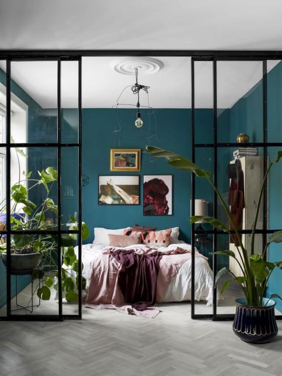 Makuuhuoneen lasiseinät luovat kynnyksettömän vihreän keitaan, jossa on sinivihreät ruukut