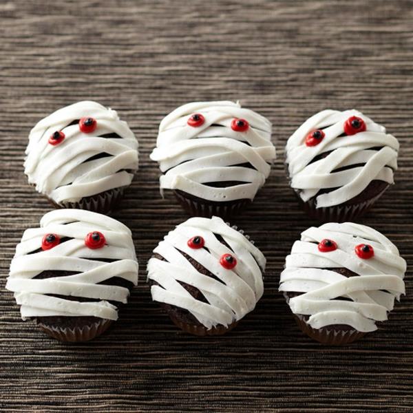 Pelottavia muffinsseja, joissa leivotaan halloween -leivonnaisia ​​cupcakes -muumioita