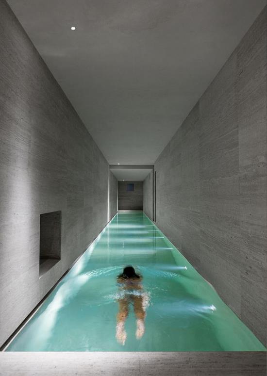 Sisäuima-allas kotona puhdasta minimalismia pitkänomainen muoto tyttö veden harmaissa laatoissa sisäänrakennettu valaistus