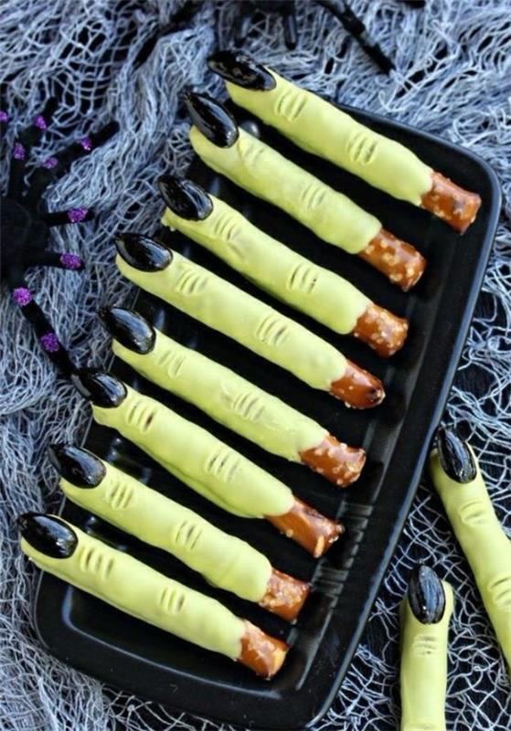 Halloween -välipaloja lapset leipovat runsaita sormiruoan pretzel -tikkuja noidan sormilla