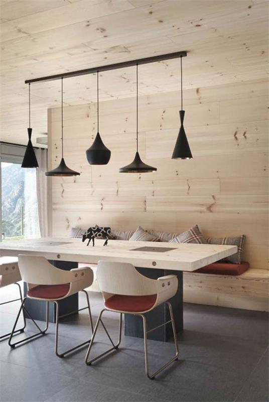 Vaaleaa puuta sisätiloissa ruokasali ruokapöytä tuolit penkki seinään vaaleilla puulla verhottu riippuvalaisimet