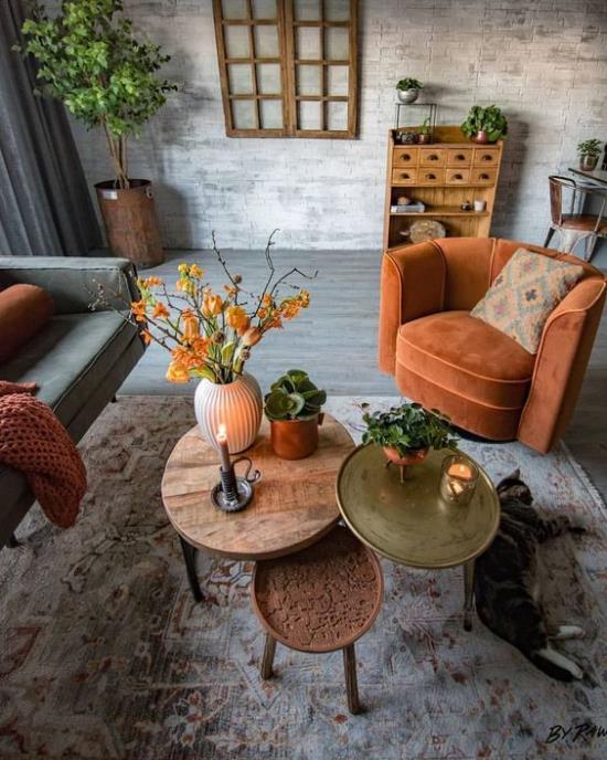 Syksyn sisustus olohuoneessa oranssinvärinen nojatuoli, kolme pientä pyöreää pöytää sisustettu erittäin kodikkaalla ilmapiirillä