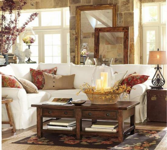 Syksyn sisustus olohuoneessa valkoinen kulmasohva puinen pöytä koristeltu värikkäillä tyynyillä kynttilät oksat maljakossa kodikas ja kodikas