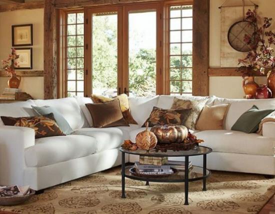 Herbstdeko olohuoneessa valkoinen sohva heittää tyyny kurpitsan lehdet maljakoihin