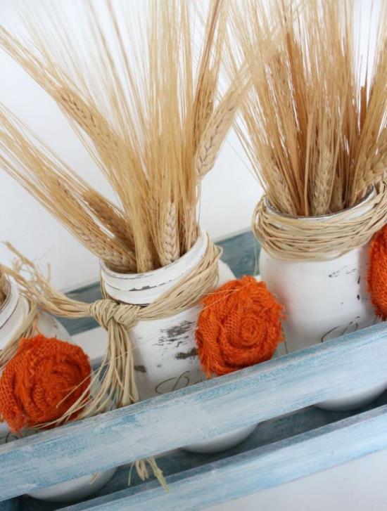 Syksyn koristelu vehnälasilla, jotka on maalattu valkoisiin vehnänvarreihin, neulottuja kukkia oranssissa maaseudun koristuksessa